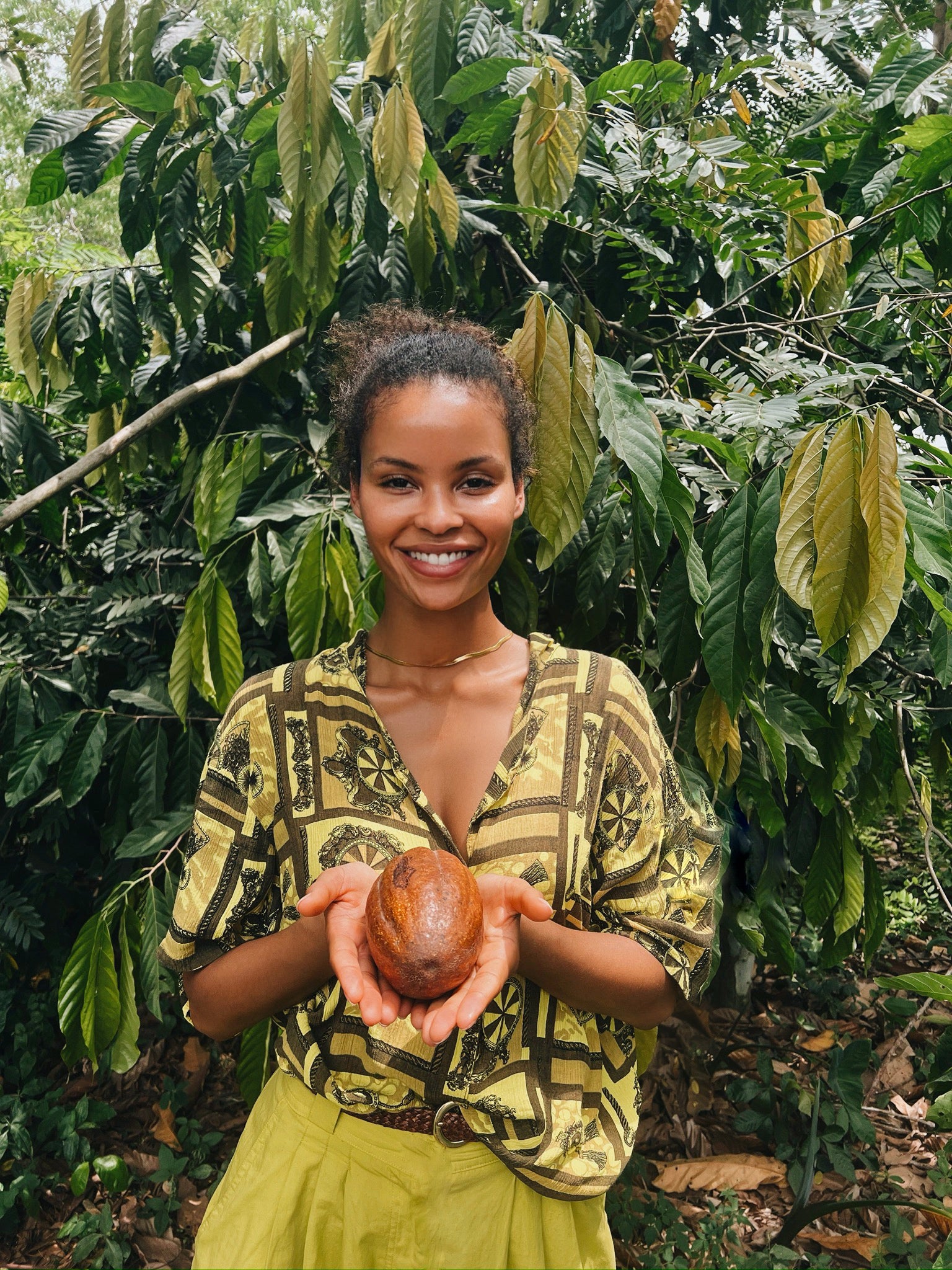 Zaina Gohou, Zacao founder, holding cacao pod on Ghanaian cacao farm.