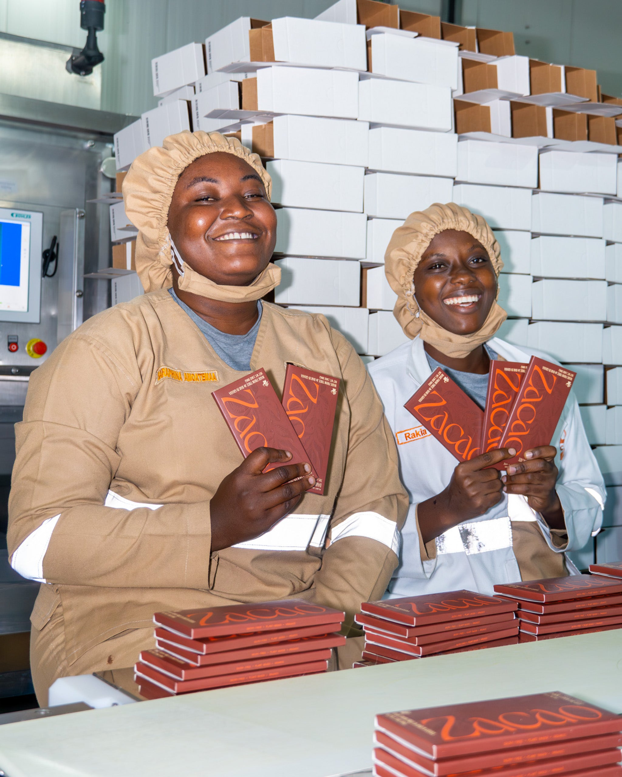 Two smiling Zacao team members packaging freshly made chocolate bars at Ghana factory.